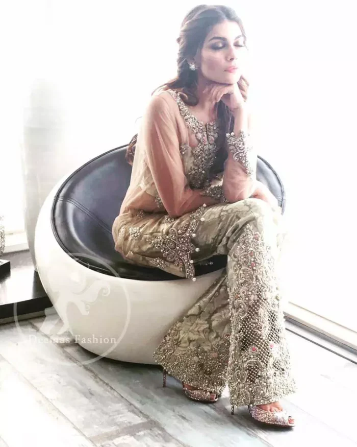 A straight short shirt with having Round neckline features beautiful embellishments on the neckline. Embellished border implemented at the bottom of shirt. Sleeves contain embroidered motifs on the cuff. Banarsi Jamawar Bell bottom pants. Dupatta contains stones spray all over and Edges finished.