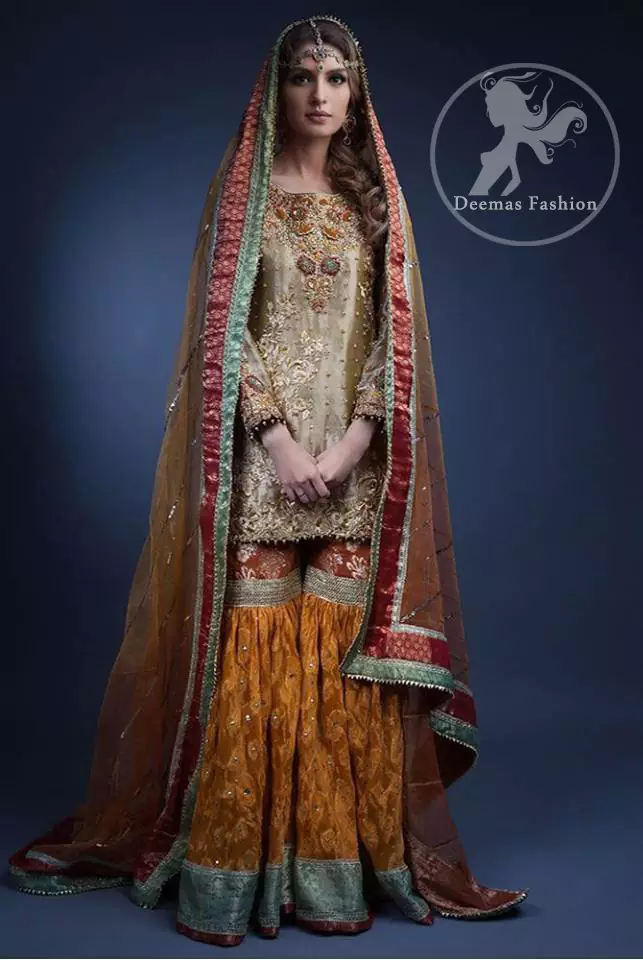 The shirt features beautiful lovely embellishments on the neckline. Embellished border implemented on hemline. Full sleeves contain embroidered borders on the cuff. Rust and mustard banarsi jamawar chiffon gharara has small motif spay scattered all over it. Finished with laces and multi-colour banarsi jamawar.