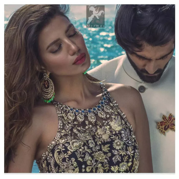 Charade net peplum having halter neckline. Peplum adorned with light golden, pearls and mix embellishment. Husk net sharara and dupatta. Sharara having hemline and small motifs spray all over it. Dupatta having zigzag border on sides, beautiful shapes of motifs on small sides (pallu) and appliqued with charade.