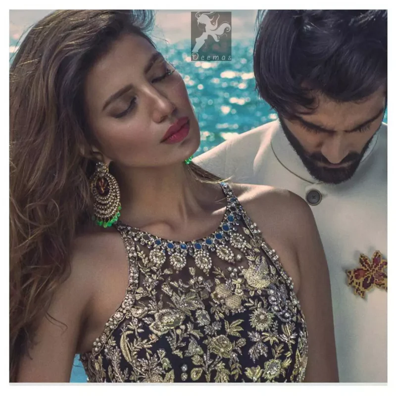 Charade net peplum having halter neckline. Peplum adorned with light golden, pearls and mix embellishment. Husk net sharara and dupatta. Sharara having hemline and small motifs spray all over it. Dupatta having zigzag border on sides, beautiful shapes of motifs on small sides (pallu) and appliqued with charade.