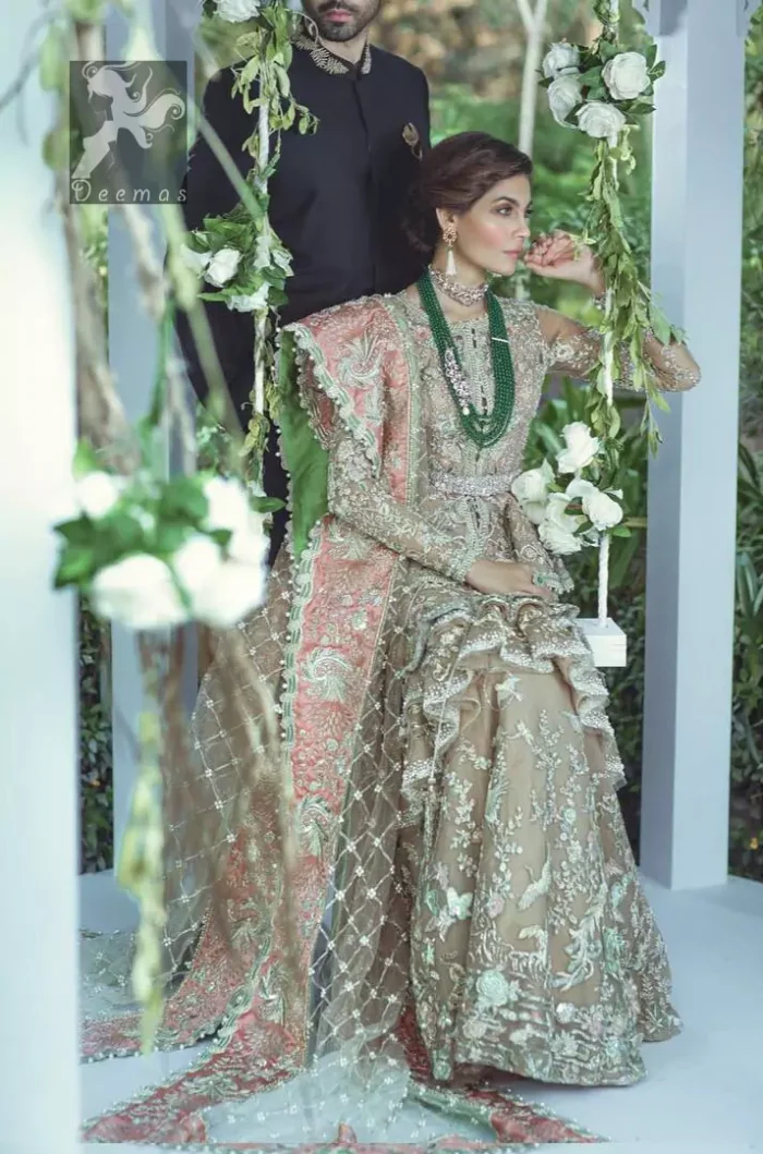 Fawn short length peplum made with net having embellished belt on waist. Large embellished border having peach appliqued on dupatta. Dupatta is adorned with rectangular shapes of embellishment small motifs all over it. Fitted lehenga having extra layer above the knees.