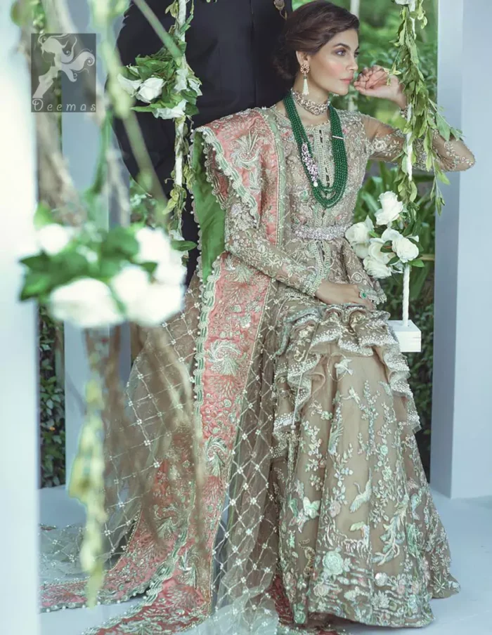 Fawn short length peplum made with net having embellished belt on waist. Large embellished border having peach appliqued on dupatta. Dupatta is adorned with rectangular shapes of embellishment small motifs all over it. Fitted lehenga having extra layer above the knees.