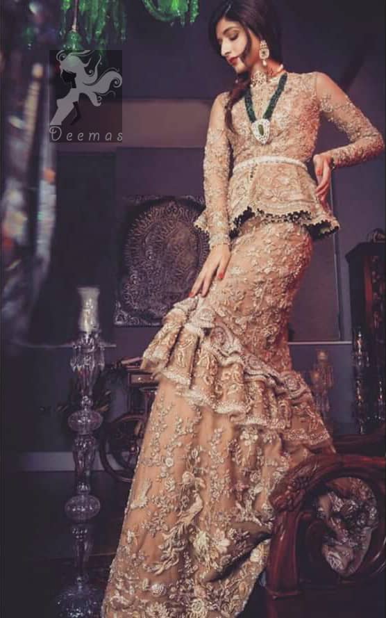 Fawn short length peplum made with net having embellished belt on waist. Large embellished border having peach appliqued on dupatta. Dupatta is adorned with rectangular shapes of embellishment small motifs all over it. Fitted lehenga having extra layer above the knees.