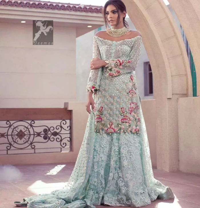 Sweetheart neckline pure crinkle chiffon shirt adorned with embellishment. Embellishment includes majorly light golden, silver, shocking pink and mehndi green shades. Shirt comes with embroidered sharara and net dupatta.