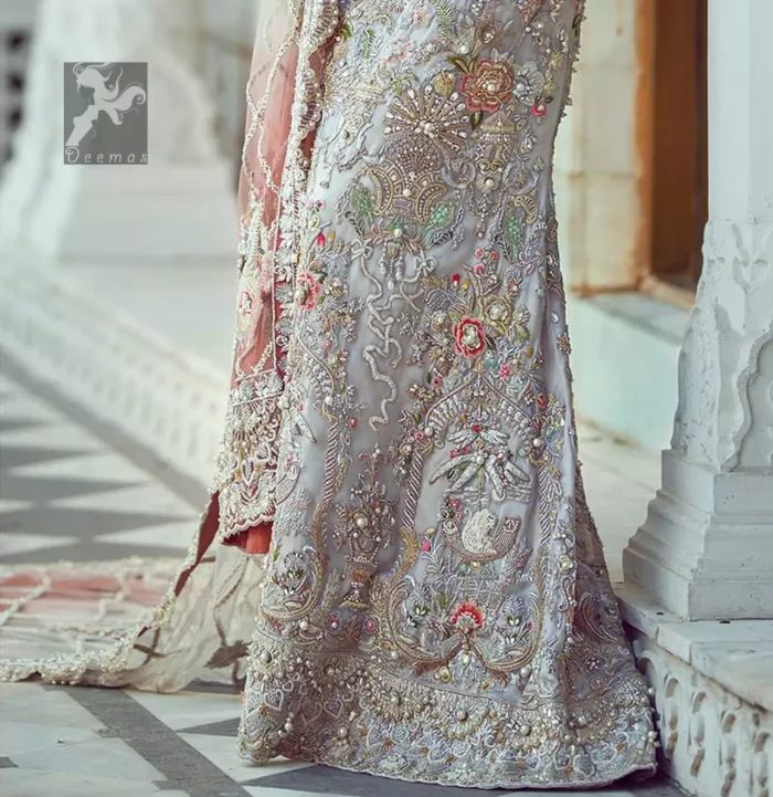 Ivory white long fitted bridal maxi. Maxi adorned with colorful embellishment using appliques and threads. Bridal maxi comes with two tones dupatta having peach and ivory white shades.