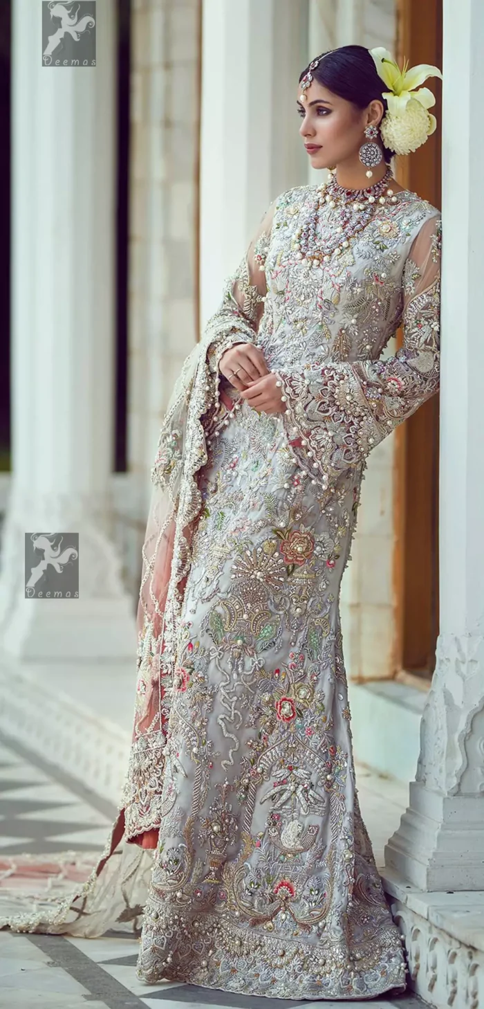 Ivory white long fitted bridal maxi. Maxi adorned with colorful embellishment using appliques and threads. Bridal maxi comes with two tones dupatta having peach and ivory white shades.