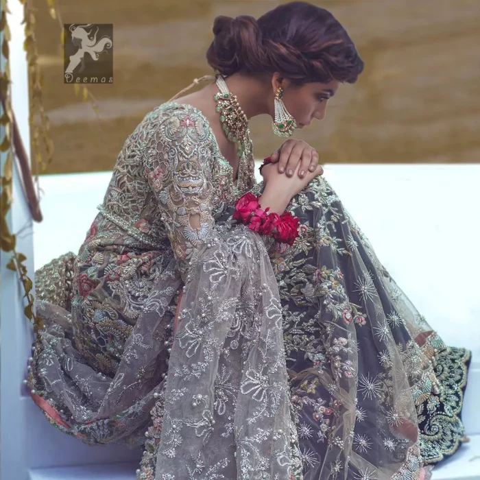 Light grayish fawn net maxi and dupatta. Bridal maxi adorned with silver, light golden, antique shades and colorful thread embellishment. Light grayish fawn net dupatta adorned with embellished border and large motifs all over it. Blackcurrant velvet sharara adorned with silver and light golden embellished border.