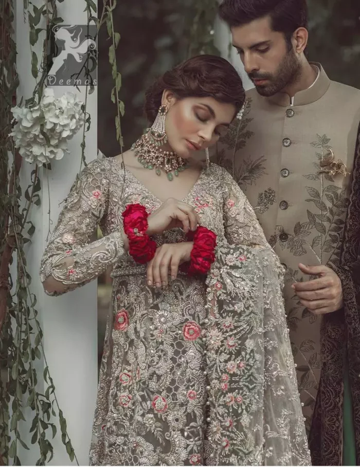 Light grayish fawn net maxi and dupatta. Bridal maxi adorned with silver, light golden, antique shades and colorful thread embellishment. Light grayish fawn net dupatta adorned with embellished border and large motifs all over it. Blackcurrant velvet sharara adorned with silver and light golden embellished border.