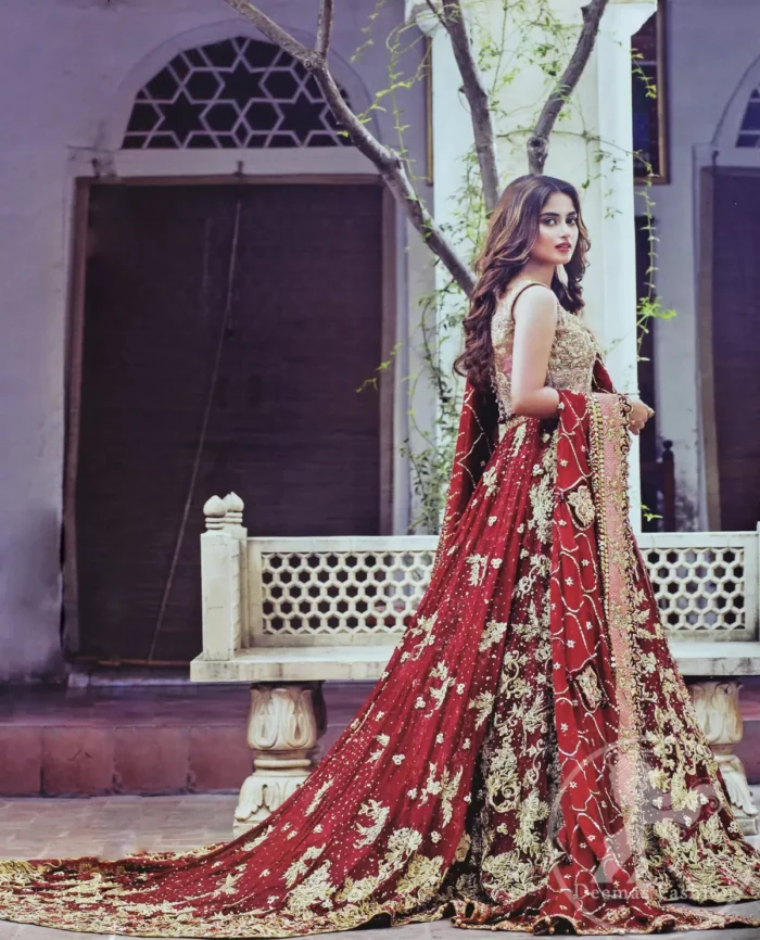 Frock having intricately embellished brown bodice and deep red frock embellished with tea pink, golden and brown shaded kora, dabka, naqshi, sequins, beads and pearls. This outfit is beautifully coordinated with brown embellished lehengha. Lehengha is embellished with a larger border. This outfit is enhanced by a thick floral embellished pattern. Back has small flowery pattern all over it. Dress comes with red dupatta decorated with four sided floral pattern. Wavy sequins pattern embellishment all over it.