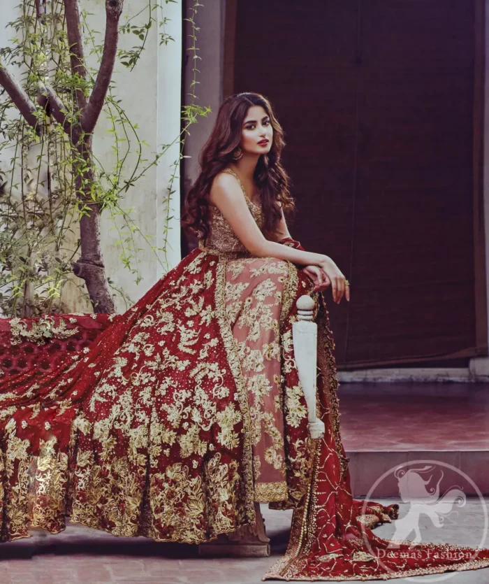 Frock having intricately embellished brown bodice and deep red frock embellished with tea pink, golden and brown shaded kora, dabka, naqshi, sequins, beads and pearls. This outfit is beautifully coordinated with brown embellished lehengha. Lehengha is embellished with a larger border. This outfit is enhanced by a thick floral embellished pattern. Back has small flowery pattern all over it. Dress comes with red dupatta decorated with four sided floral pattern. Wavy sequins pattern embellishment all over it.