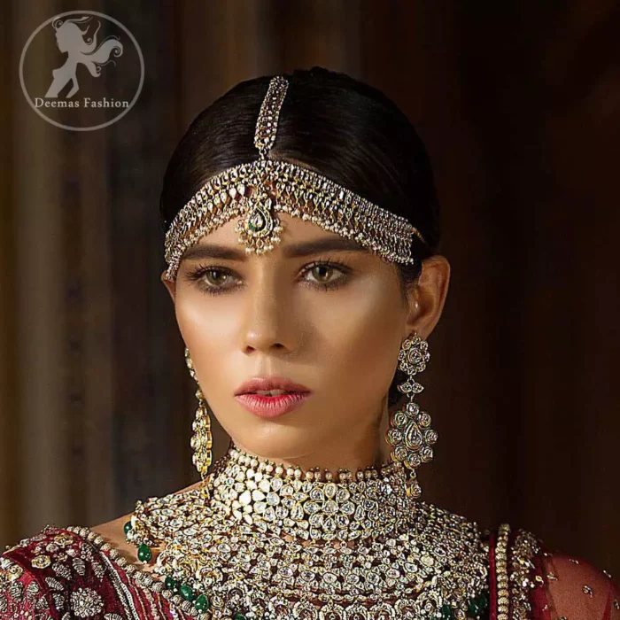 This maroon angrakha frock heavily embellished in the front with silver gold kora dabka, kundan and stones work. One side shoulder neckline is beautifully ornamented with sequins lines in geometric manner. Paired up with matching brocade sharara which looks so magnificent. This outfit is meticulously coordinated with maroon dupatta with embellished borders on lengths.