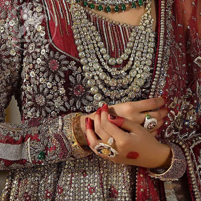 This maroon angrakha frock heavily embellished in the front with silver gold kora dabka, kundan and stones work. One side shoulder neckline is beautifully ornamented with sequins lines in geometric manner. Paired up with matching brocade sharara which looks so magnificent. This outfit is meticulously coordinated with maroon dupatta with embellished borders on lengths.