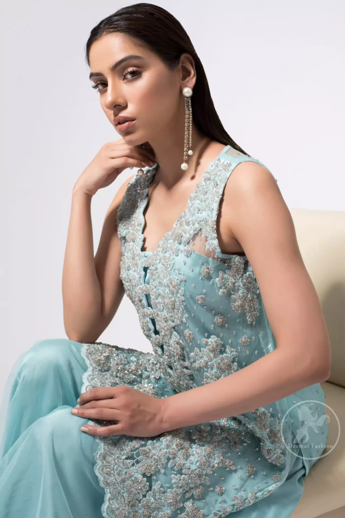 This classic shadow green shirt, meticulously highlighted with silver kora, dabka, tilla, sequins and pearls. This dress is adorned with floral motifs. Complete the look with trimming hemline embellished with heavy embroidery. It comes with shadow green organza sharara. This outfit is beautifully decorated with chiffon dupatta having sprinkled sequins all over it.