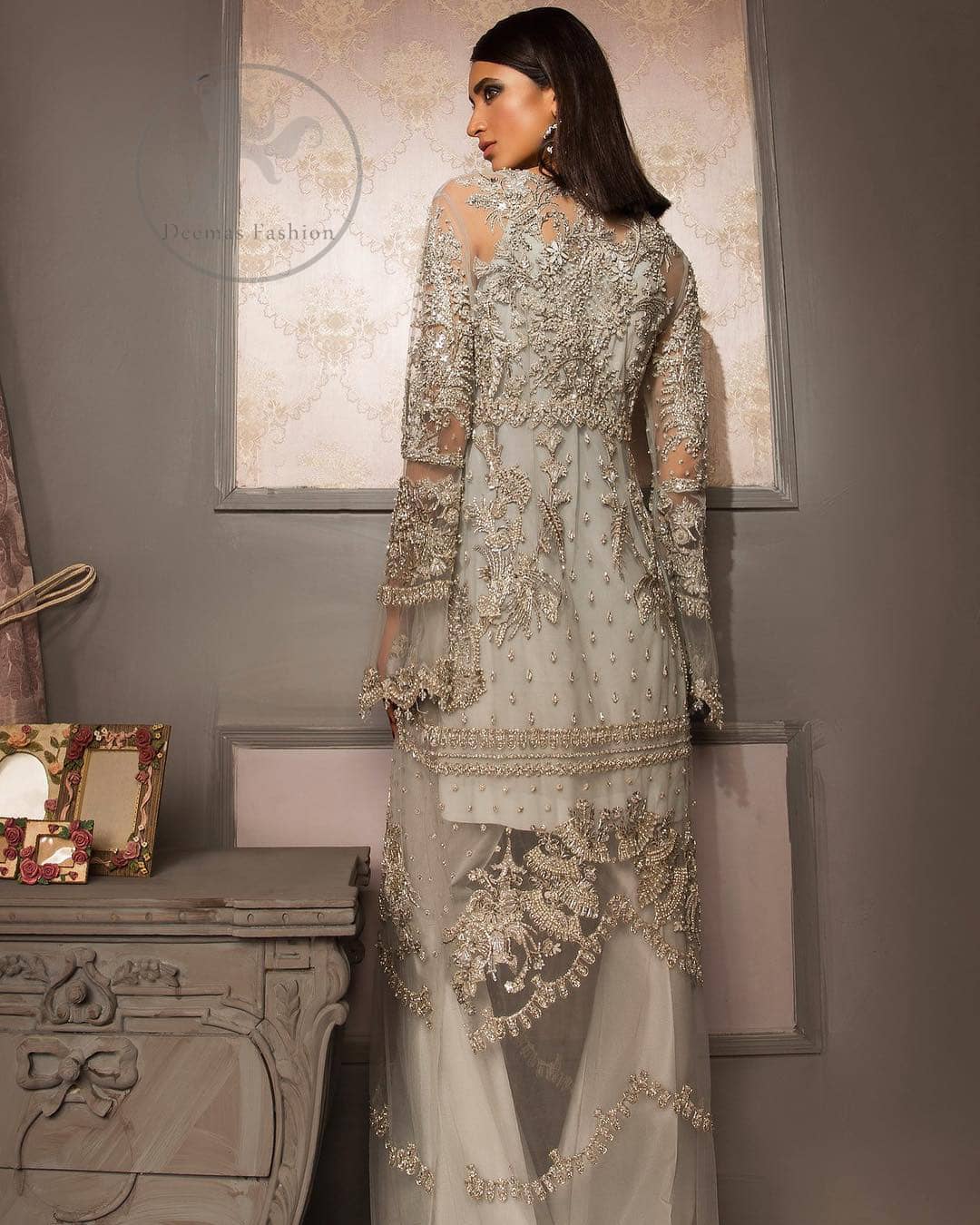 This beautiful gown is decorated with resham thread, kora, dabka, tilla, sequins and pearls. It is sculptured with floral thread embroidery. Sleeves are bell shaped and fully embroidered. It comes with brocade straight trouser. It is beautifully coordinated with organza dupatta.