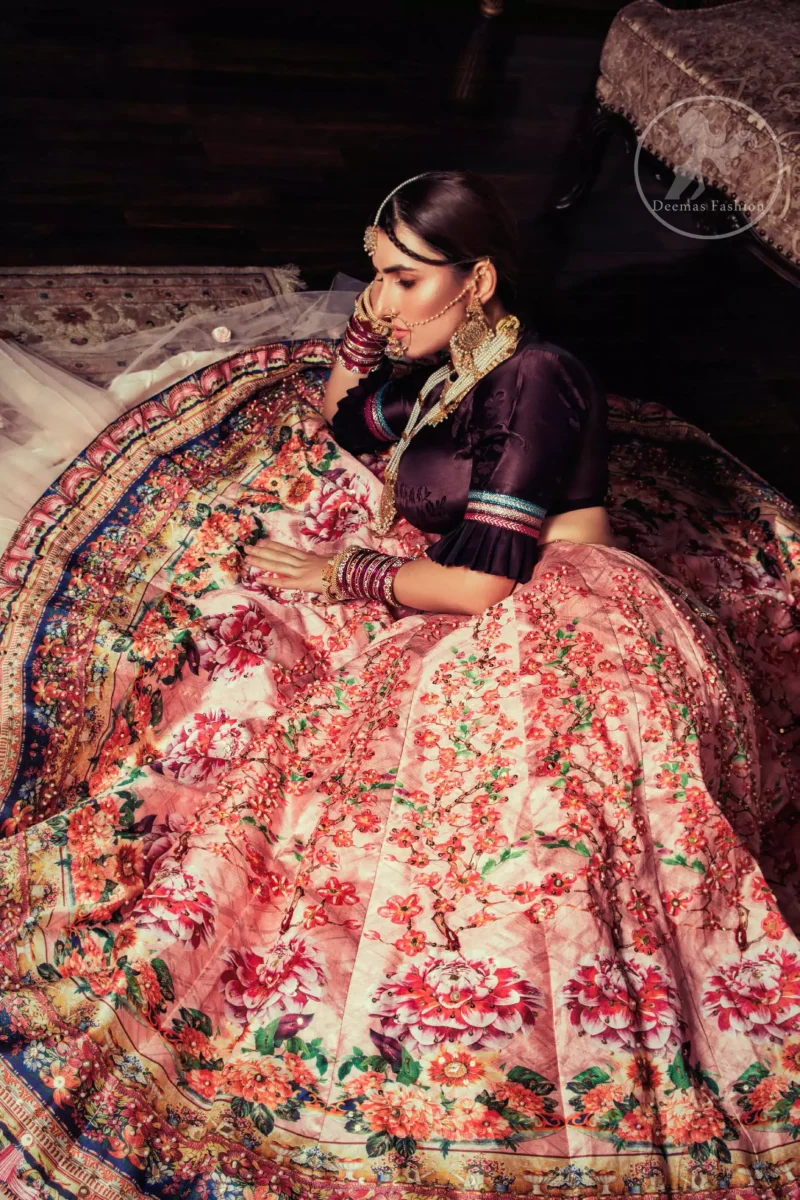 This outfit is a timeless beauty. Dark purple self-printed blouse is decorated with applique. The raw silk classic lehenga is adorned with digital print. Its floral print is further decorated with swarovski, tilla, kora dabka . Its beautiful printed border adds to the look. This outfit is beautifully coordinated with peach pink dupatta with heavy embroidered borders.