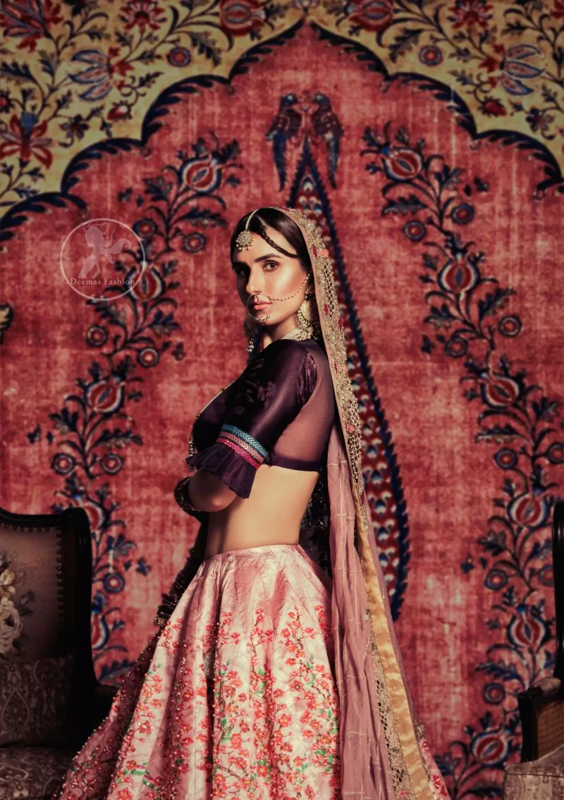 This outfit is a timeless beauty. Dark purple self-printed blouse is decorated with applique. The raw silk classic lehenga is adorned with digital print. Its floral print is further decorated with swarovski, tilla, kora dabka . Its beautiful printed border adds to the look. This outfit is beautifully coordinated with peach pink dupatta with heavy embroidered borders.