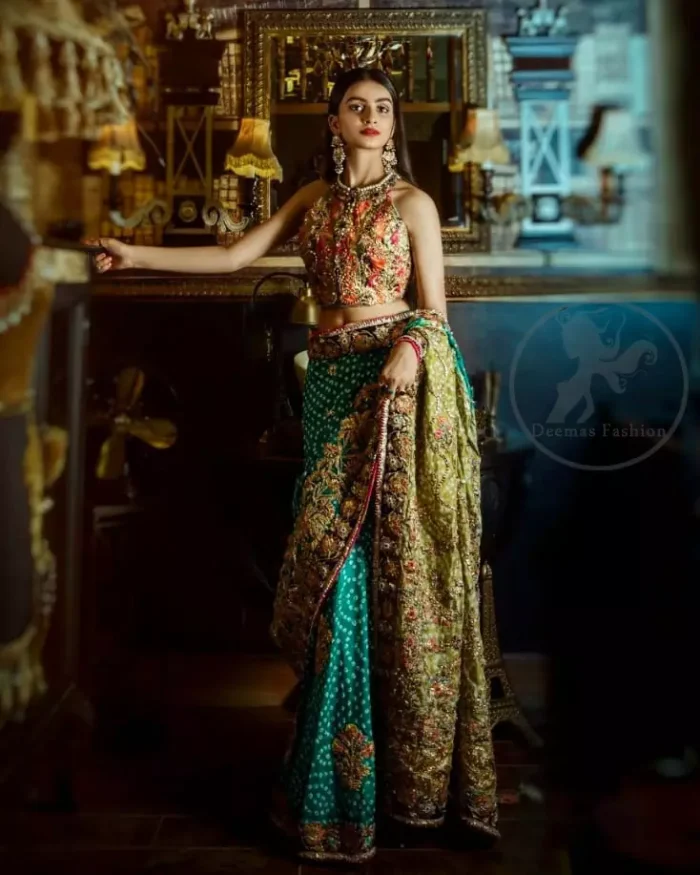 This outfit is a timeless beauty. It is heavily embellished with antique gold kora, dabka, tilla, sequins and swarovski crystals. This exquisite halter neckline blouse is fully decorated with floral motifs patterns all over it. Applique waist belt is decorated with gota and thread embroidery.It comes with embellished lehengha. This Outfit is beautifully coordinated with lime yellow dupatta with heavy embroidered borders.