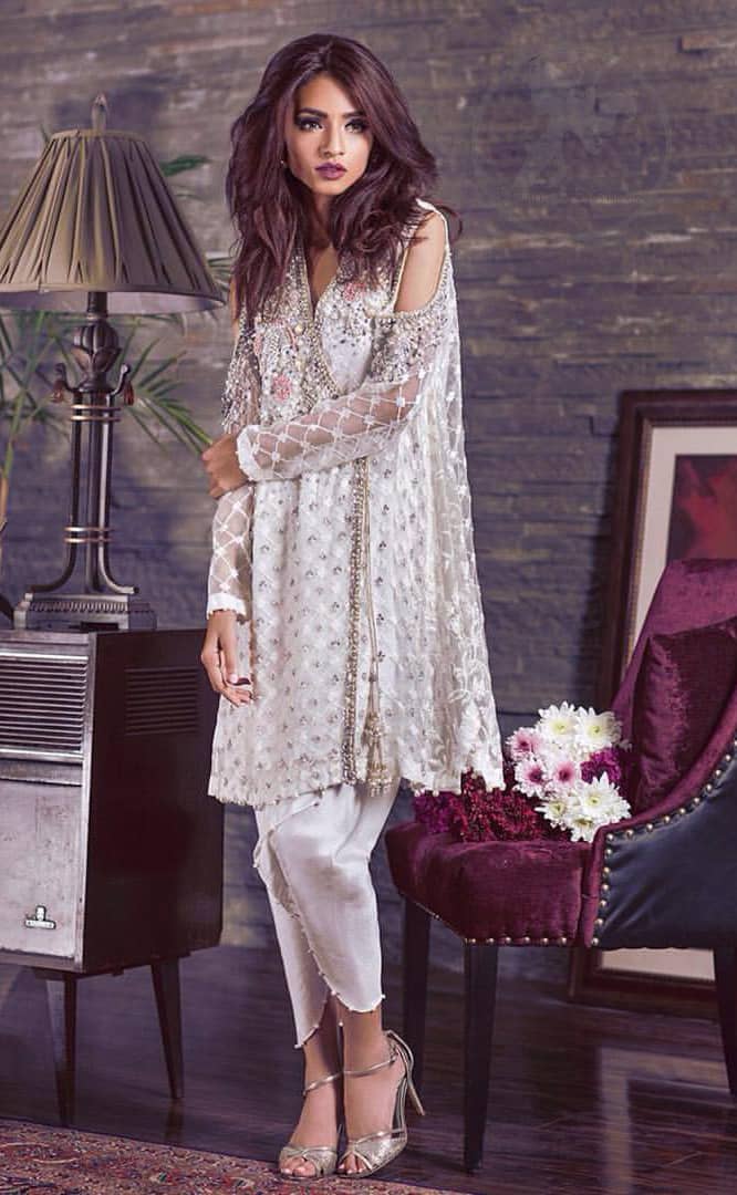 This beautiful angrakha style shirt adorned with embroidered featuring silver and antique shaded kora dabka, tilla, sequins and swarowski. Hemline is decorated with pearls. There is cold shoulder design on sleeves which adds to the look. It comes with brocade pajama.It is coordinated with net dupatta having sprinkled sequins all over it.