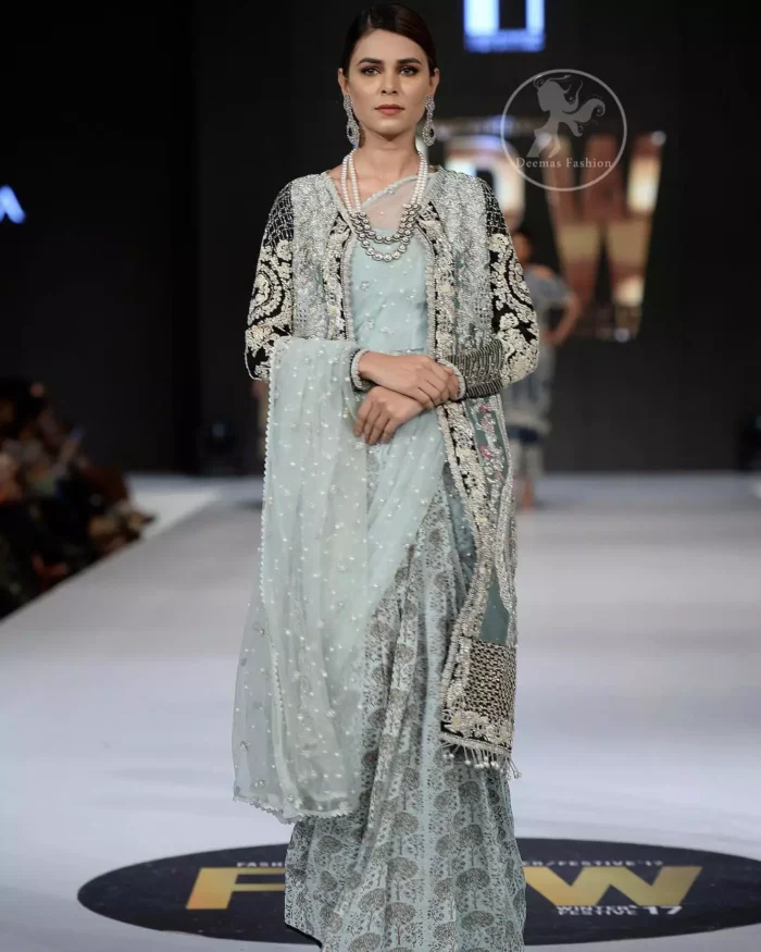 This outfit is a timeless beauty. The blouse is covered with gown embellished with silver gold kora dabka, Sequins and swarovski crystals.This exquisite gown is decorated with embroidered black applique and tassels on hemline.It comes with lehenga style bottom. This Outfit is beautifully coordinated with strip of material that wrapped around the blouse and draped across the front and over one shoulder?