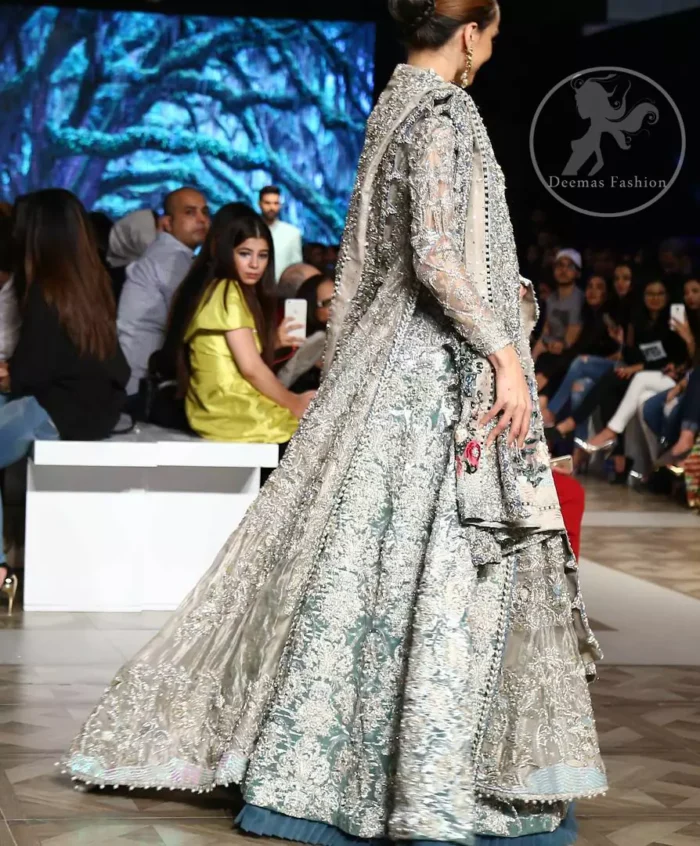 This outfit is a timeless beauty. It is heavily embellished with silver gold kora dabka, Sequins and swarovski crystals. This exquisite Pishwas is fully decorated with floral motifs patterns all over it. It is further enhanced with multiple colored Foral thread embroidery. The applique border of pishwas is ornamented with small silver pearls. It comes with embellished lehenga which has small sized sprinkled floral motifs all over. This Outfit is beautifully coordinated with matching Dupatta with heavy embroidered borders.