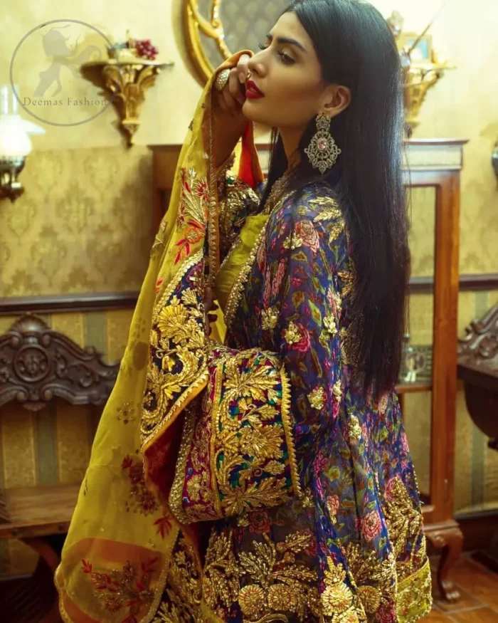 This  royal blue angrakha shirt is embellished with resham thread. It is meticulously highlighted with dull golden kora dabka, tilla,  sequins and pearls. Sleeves and neckline are adorned with gotta work as well. Hemline is allured with embroidered applique. It comes with embellished gharara which has sprinkled floral motifs. This Outfit is beautifully coordinated with yellow dupatta with heavy embroidered borders.