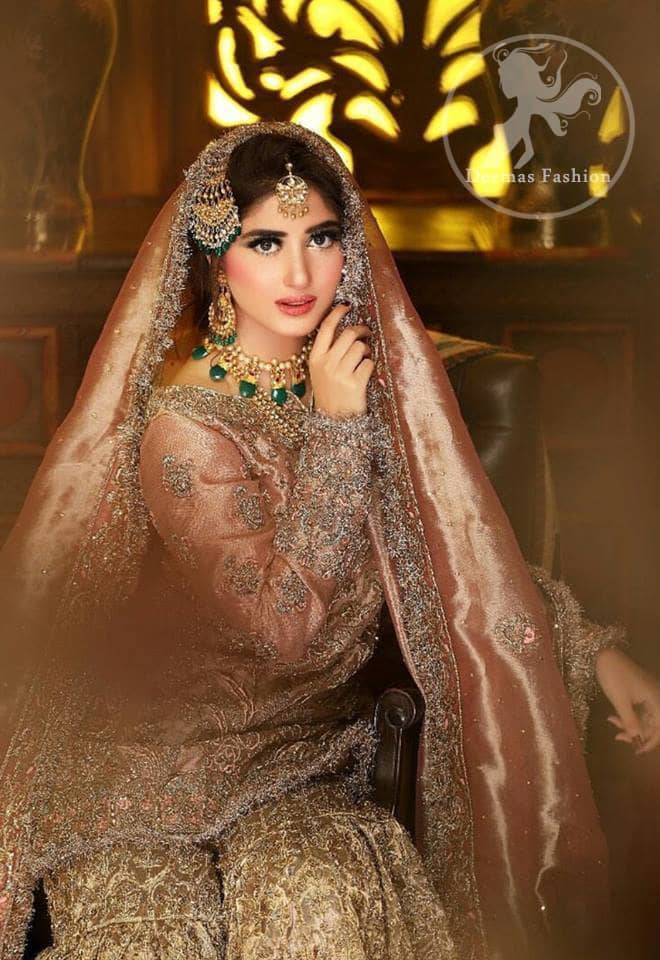 Feel glamorous in antique brass short shirt with fascinating embellishment on neckline with golden kora dabka, tilla and pearls. Floral motifs on sleeves add to the look. It is stunningly coordinated with traditional golden gharara. Complete the look with tilla work organza dupatta finessed with embroidered borders.