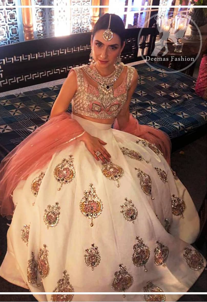 The blouse is beautifully embellished with cutwork embroidery enhanced with silver gold kora dabka, kundan and sequins work. It is paired up with ivory lehenga with colorful pattern embellishment ornamented with kora dabka, and colorful thread embroidery. It comprises with peach dupatta sprinkled sequins all over.
