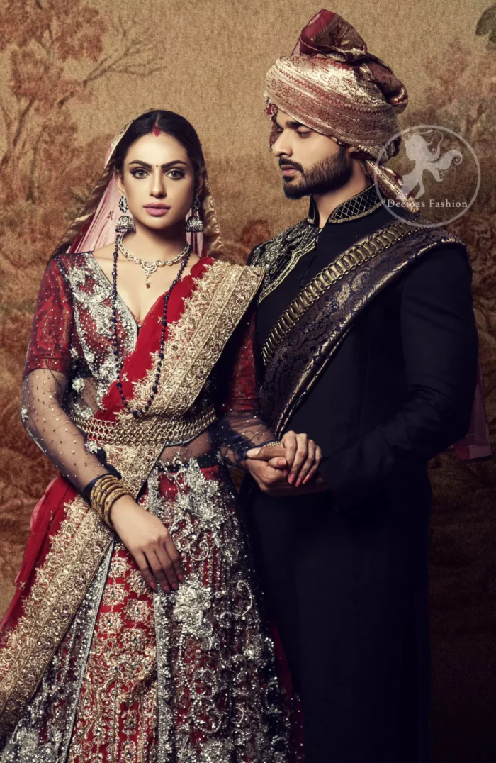 This dress is timeless beauty. Black floor length net paneled gown is beautifully embellished with silver kora dabka, tilla, pearls and sprinkled sequins all over. It comprises with maroon blouse and skirt. The skirt is ornamented with floral motifs done with silver gold kora dabka, tilla, kundan and sequins work. This outfit is coordinated with maroon dupatta with embroidered borders on all four sides and sequins work on the ground.