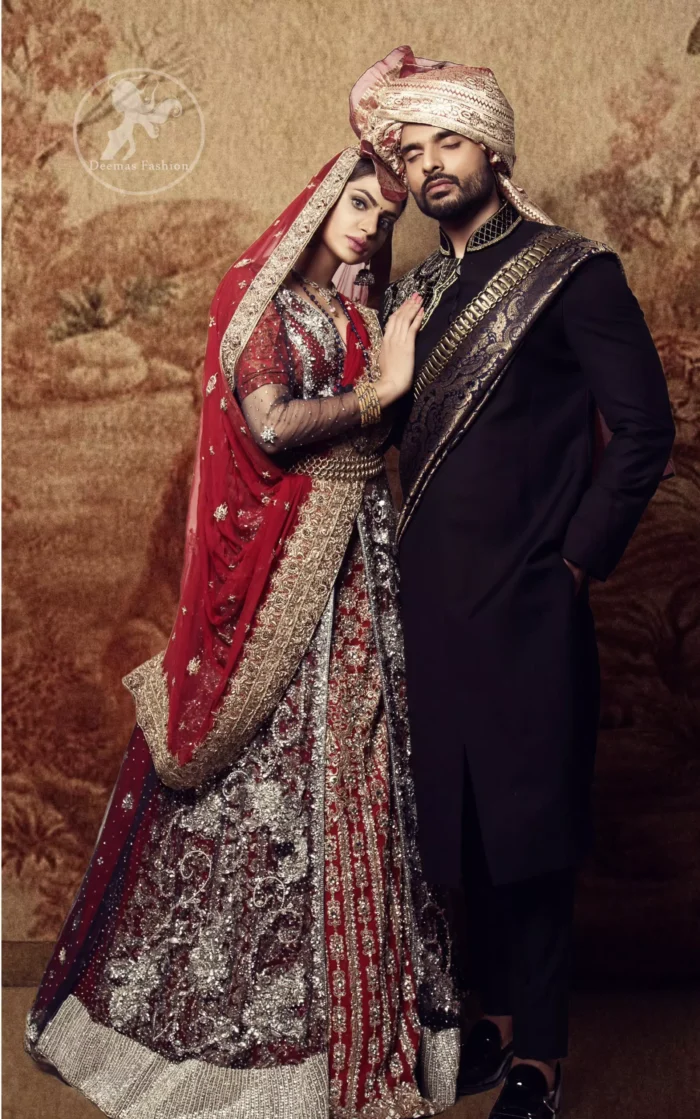 This dress is timeless beauty. Black floor length net paneled gown is beautifully embellished with silver kora dabka, tilla, pearls and sprinkled sequins all over. It comprises with maroon blouse and skirt. The skirt is ornamented with floral motifs done with silver gold kora dabka, tilla, kundan and sequins work. This outfit is coordinated with maroon dupatta with embroidered borders on all four sides and sequins work on the ground.