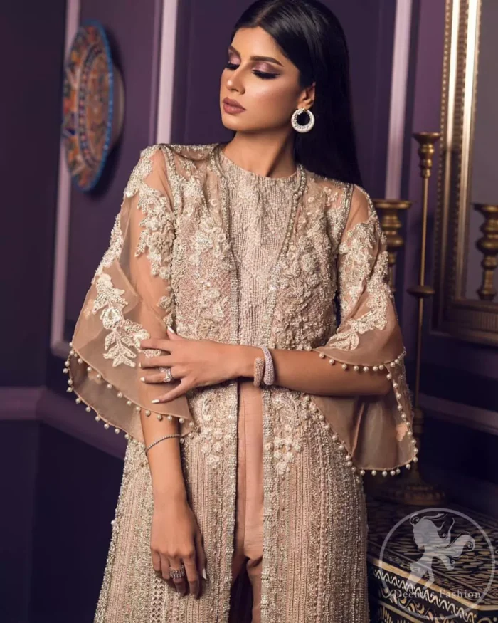 This dress is decorated with floral embroidery. It is highlighted with kora, dabka, tilla, sequins and pearls. Gown is adorned with scalloped border and tassels which adds to the look. It comes with trousers. It is coordinated with organza dupatta which is sprinkled with sequins all over it.