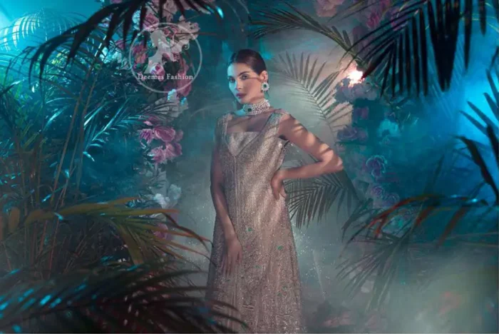 This dress is decorated with floral embroidery. It is highlighted with kora, dabka, tilla, sequins and pearls. Back trail frock adds to the look. It is allured with shamoz lining. It is coordinated with shamoz sharara. It comes with chiffon dupatta which is sprinkled with sequins all over it.