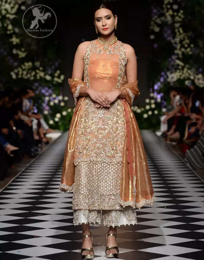 This outfit is stunningly perfect for any evening ensemble. It is paired with a sleeveless double layered shirt in organza fabric which is extensively hand worked in crystals and zardozi. This dress is beautifully sculptured with dull golden floral embroidery, adorned with cutwork borders embellished with tassels, kora, dabka, pearl and sequins work all over. It comes with embroidered trousers. It is coordinated with tissue dupatta which is furnished with four sided scalloped border.