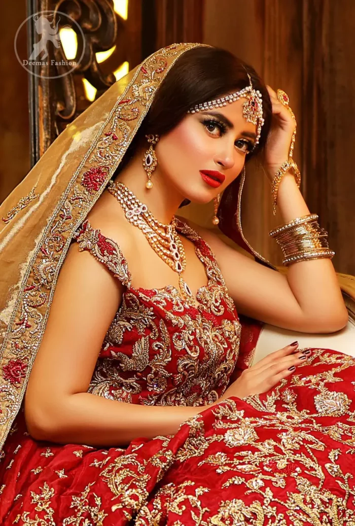 Reflecting royalty and the majestic beauty of statuesque shape and silhouette this bridal dress is perfect for your special day. Feel glamorous in this floor length maxi with fascinating embellishment around the neckline with golden kora dabka, pearls and sequins. It is further enhanced with floral motifs and heavy embroidered bottom. The hemline is decorated with heart shape motifs all around the bottom of maxi. It comprises with brocade pajama and golden dupatta having four sided embroidered borders and sprinkled small motifs on ground.