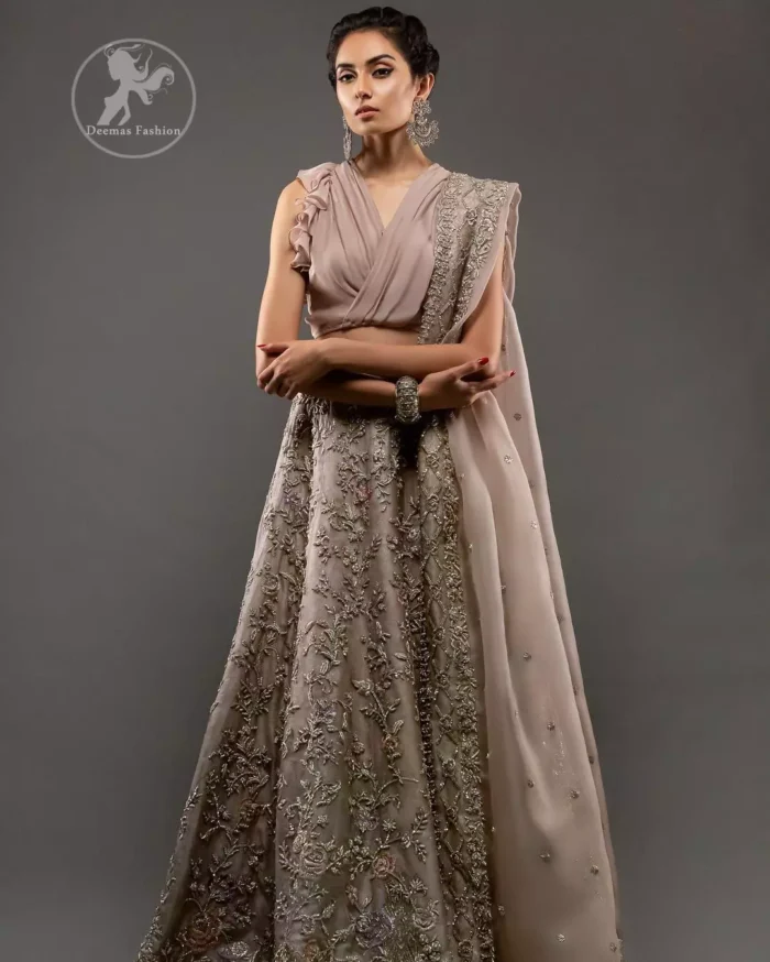 Commemorating the juxtaposition of traditions and modern sensibility with sensuous silhouettes and a subtle pastel palette. Feel glamorous in this stylish blouse paired up with rodeo dust lehengha. The lehengha is delicately crafted with golden kora dabka, tilla and kundan work. Multiple colored floral motifs enhanced the beauty of this outfit. It is coordinated with scalloped embellished border dupatta, also having sprinkled sequins on the ground.