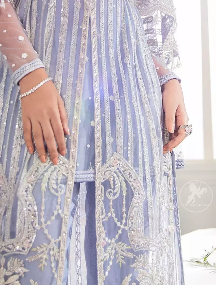 Steal the moment with our cold purple floor length gown emphasized with traditional neckline and intricate floral daaman enhanced with silver kora, dabka and sequins. It is adorned with fully embellished neckline and verticle lines, finished with floral thread embroidered hemline. Scalloped bell sleeves with tassels give it a perfect look. It comes with raw silk trousers. It is coordinated with chiffon dupatta which is sprinkled with sequins all over it.