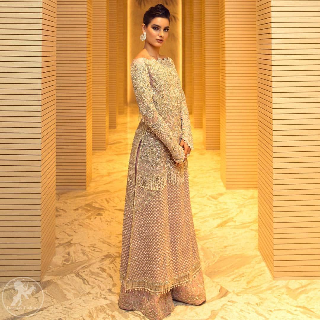 This dress is beautifully decorated with heavy embroidery. It is highlighted with dull golden kora, dabka, tilla, sequins and pearls. Fish lehengha is fully embellished.Blouse is scalloped. It comes with beautifull upper gown, sprinkled with sequins all over it. It is coordinated with chiffon dupatta which is sprinkled with sequins all over it.