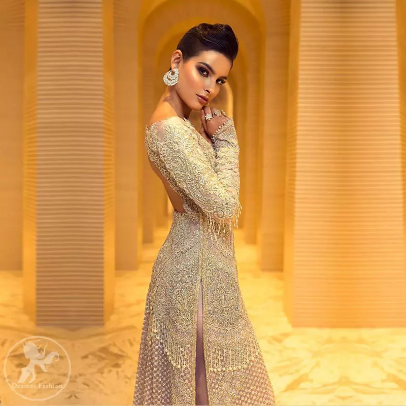 Boost your confidence and style in this glamorous attire accentuated with finest thread and zardosi work embroidery. This outfit paired up with salmon pink off shoulder long shirt embellished with thread embroidery and dull golden kora, dabka, sequins and tassels. It comes with beautifull sharara enhanced with floral motifs on the bottom. It is coordinated with chiffon dupatta which is sprinkled with sequins all over it.