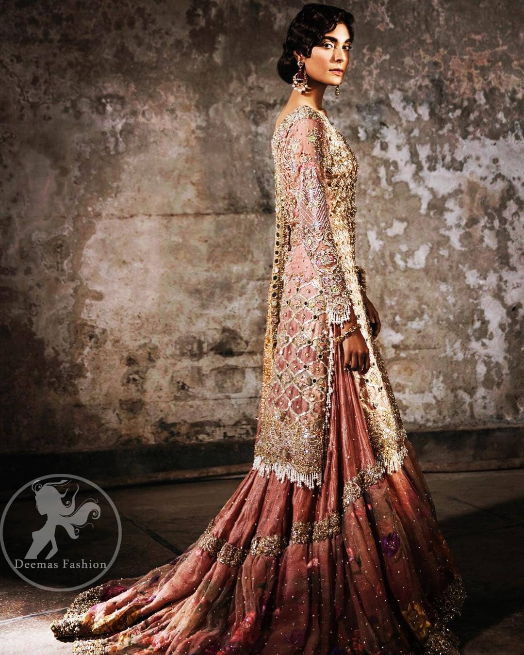 This bridal dress stands out due to its uniqueness and the perfect fusion of modern cut and traditional embroidery. It is enhanced with kora, dabka, tilla, gota, sequins and pearls. Shirt is fully embellished in crisscross pattern. It is artistically coordinated with tissue gharara which is adorned with colourful motifs and colourful embroidered dupatta detailed with gold gota work and finishing adds to the look.