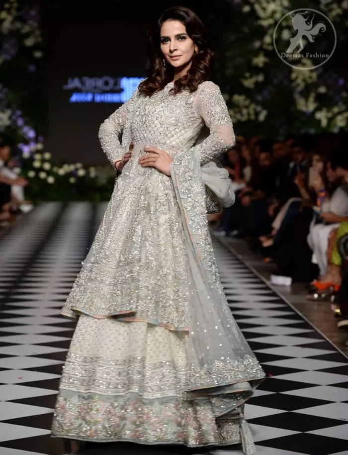 Feel glamorous in our ivory back trail frock with fascinating embellishment on neckline with silver kora, dabka, pearl and sequins. The detailed embellishment at the daaman instantly draws attention. It comes with an exquisite lehenga with thick embroidered borders to give it a regal look. The outfit is finished by beautiful applique embellished lehenga. It is coordinated with tissue dupatta which is sprinkled with sequins all over it. It is further furnished with four sided embellished border.
