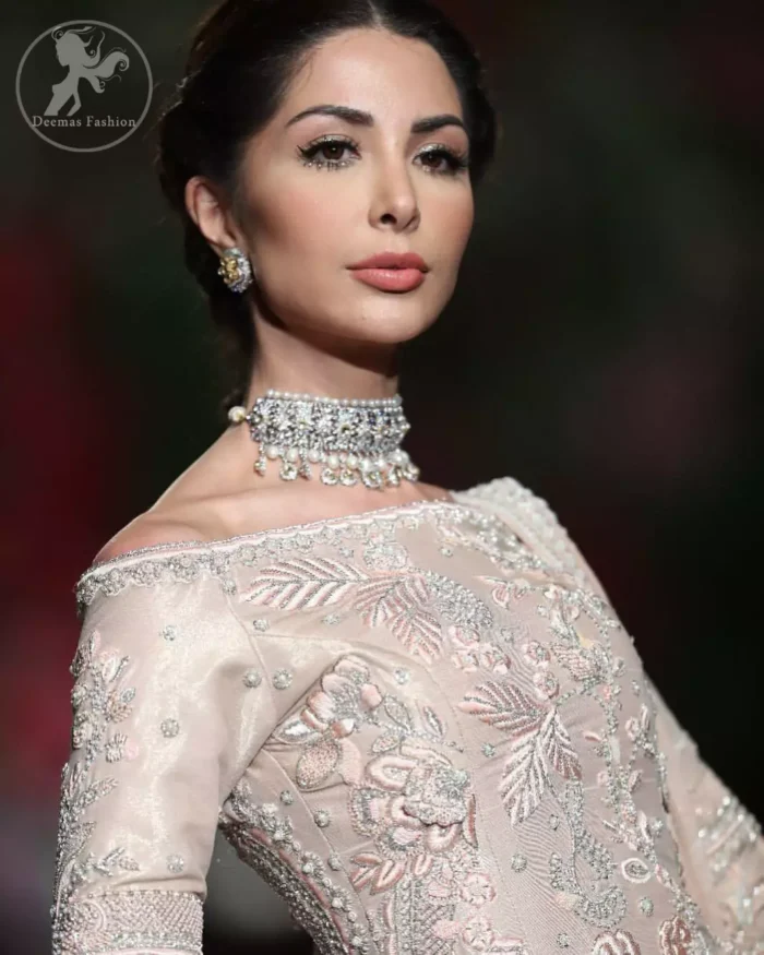 The bridal stands out due to its uniqueness and the perfect fusion of modern cut and traditional embroidery. This dress is beautifully decorated with heavy embroidery. It is highlighted with kora, dabka, tilla, sequins and pearls. It comes with embroidered sharara. It is coordinated with tissue dupatta which is sprinkled with sequins all over it. It is further furnished with four sided scalloped border.