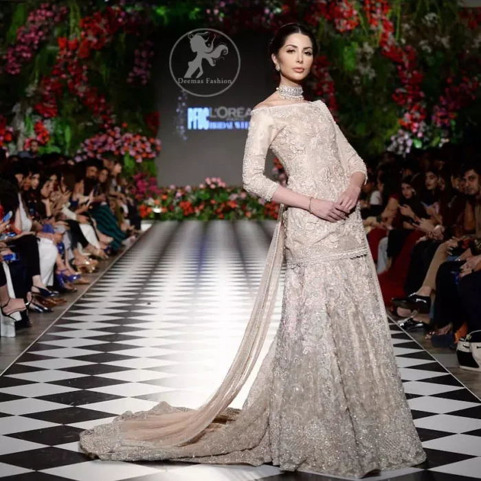 The bridal stands out due to its uniqueness and the perfect fusion of modern cut and traditional embroidery. This dress is beautifully decorated with heavy embroidery. It is highlighted with kora, dabka, tilla, sequins and pearls. It comes with embroidered sharara. It is coordinated with tissue dupatta which is sprinkled with sequins all over it. It is further furnished with four sided scalloped border.