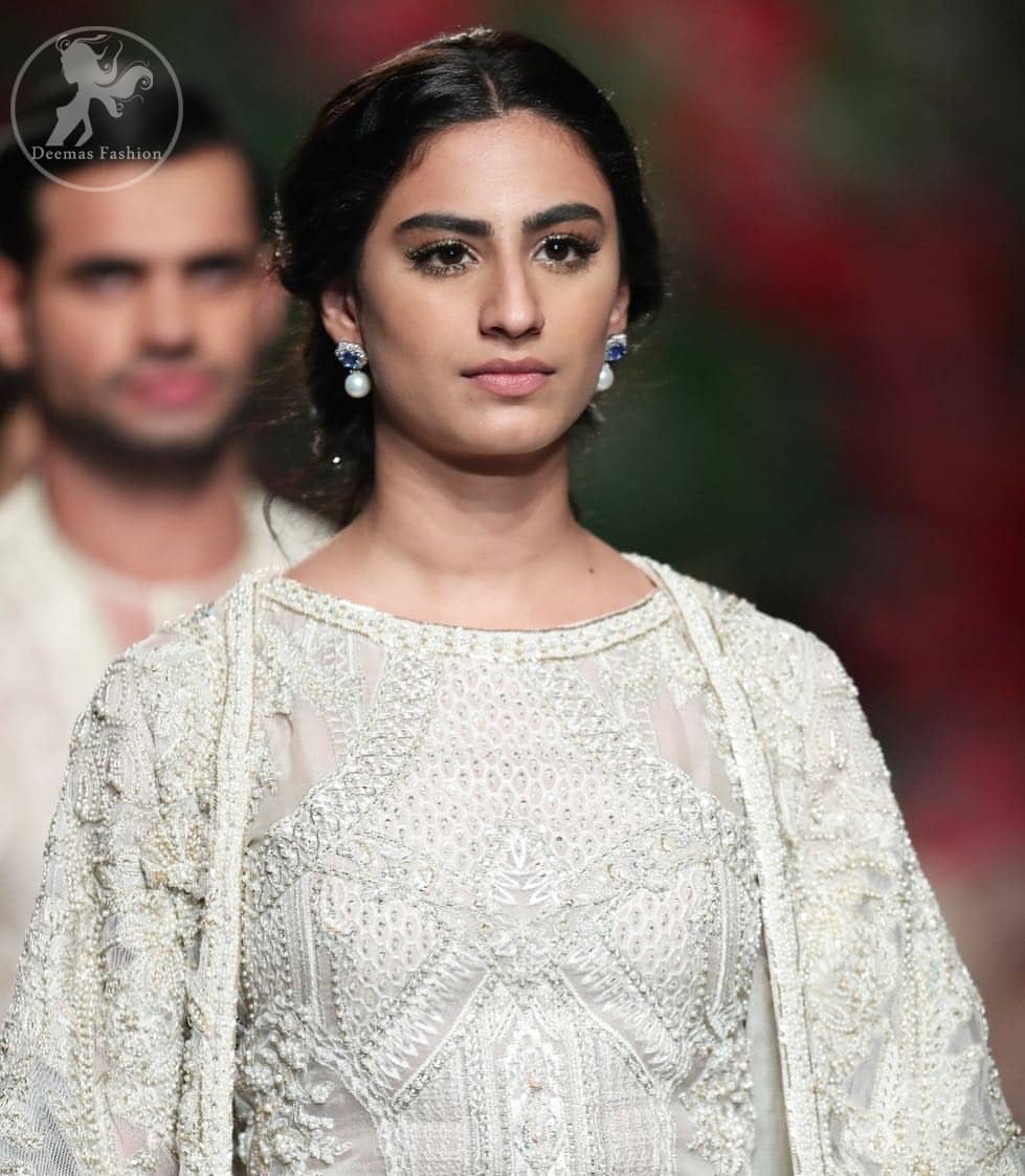 Go for this trendy dress. This dress is heavily embellished with floral and geometric styled embroidery decorated with silver kora, dabka, swarovski and pearls. Gown is enhanced with scalloped border decorated with thread clusters finishing. Third quarter sleeves are embellished with floral motifs all over along with tassels at the end. Trousers is magnificently decorated with cutwork. It is coordinated with tissue dupatta which is sprinkled with sequins all over it.