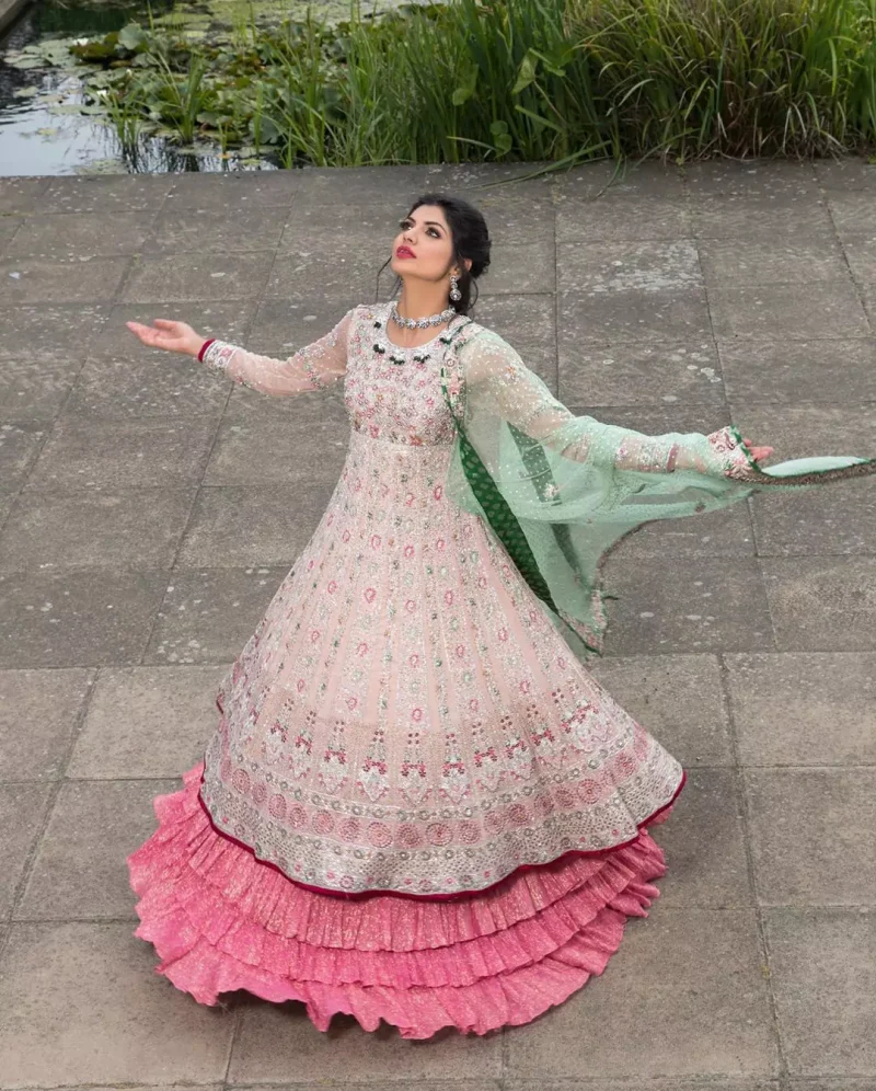 Opt for our ivory multiple-panel anarkali dress with exquisite embellishment on the bodice with pearls, sequins and silver kora, dabka. The daaman comprises of borders highlighted with floral embellished pattern. It is finished with deep blush frilled lehengha which adds to the bling. Dupatta is allured with four sided embellished border and sprinkled with stones all over it.