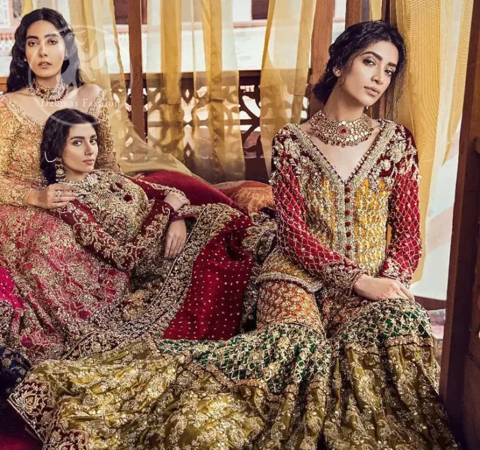 Exquisite detailing radiates elegance in this stunning short shirt. Redefine your style in this traditional and versatile ensemble ornamented with floral and geometric embroidery furnished with golden kora dabka, kundan and pearls. It comes with multiple colored traditional gharara done with zerdozi work in patterns and embroidered applique details on bottom. Complete the look with red dupatta having embroidered borders on all sides and sequins spray on the ground.