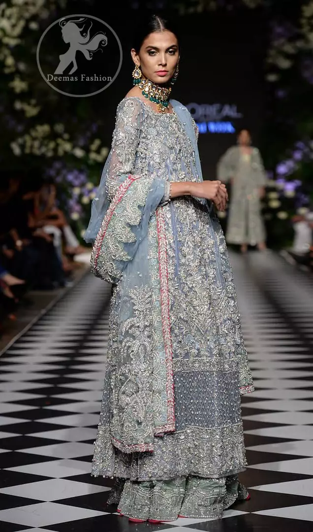 Boost your confidence and style in this glamorous attire accentuated with finest zardosi work embroidery and cut work neckline. It is beautifully decorated with heavy embroidery. It is highlighted with silver kora, dabka, tilla, sequins and pearls. It comes with heavily embroidered lehenga which is decorated with red piping from the bottom. It is coordinated with tissue dupatta which is sprinkled with sequins all over it. It is further furnished with four sided embellished border.