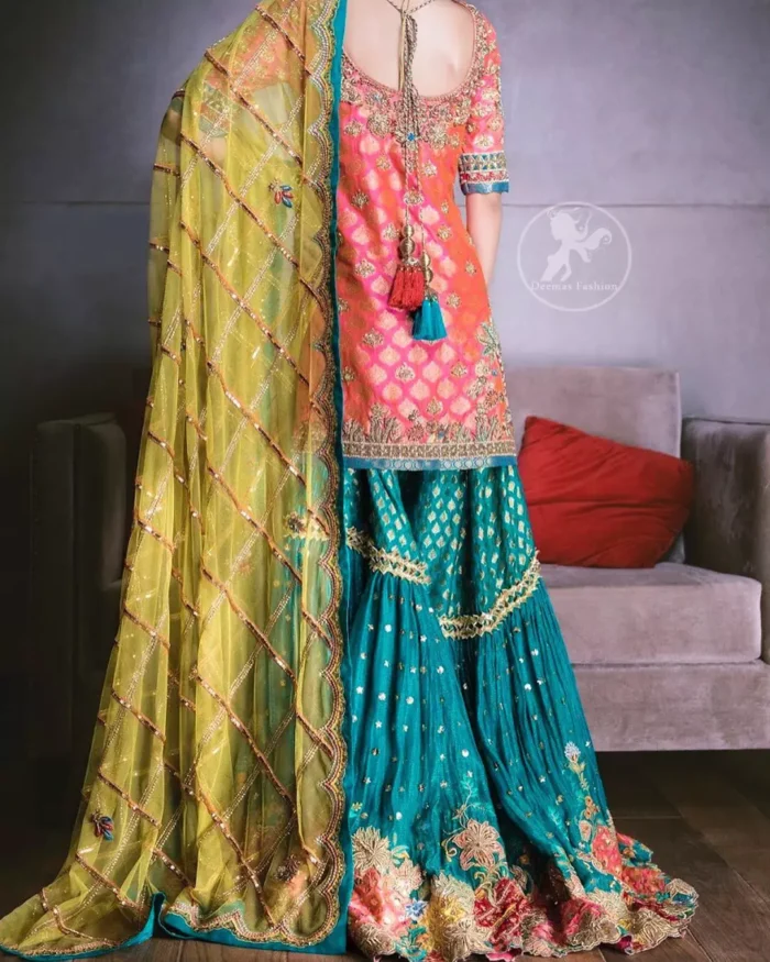 Our tea rose shirt with exquisite embellished neckline and back neckline in kora, dabka sequins and intricate thread work. The daaman is emphasized on intricate floral details that gives perfect ending to this shirt. It is coordinated with farshy gharara decorated with embroidery. The gradient turmeric dupatta has crisscross pattern and floral motifs scattered. It is finished with jamawar piping all around the edges.