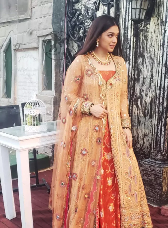 Go for this trendy dress and capture the attention in this persian red inner gold sand gown with kora, dabka and kundan embroidery. The gown is decorated with different size floral motifs and multiple color thread embroidery. Inner is enhanced with geometric pattern details on the bottom. Paired up with brocade straight trousers. It is coordinated with chiffon dupatta which is sprinkled with sequins and small floral motifs all over it. Further it has scalloped borders on all four sides embellished with zardosi work.