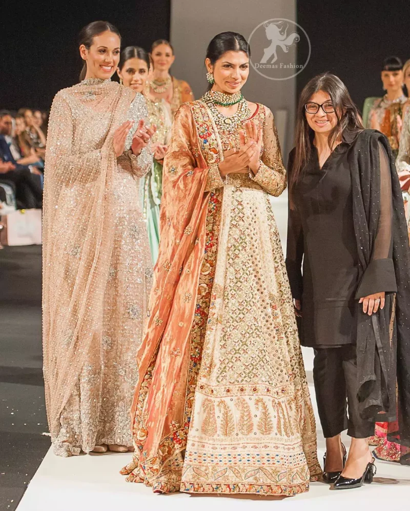 This dress is beautifully decorated with heavy embroidery. It is highlighted with dull golden kora, dabka, tilla, sequins and pearls. Fish lehengha is fully embellished.Blouse is scalloped. It comes with beautifull upper gown, sprinkled with sequins all over it. It is coordinated with chiffon dupatta which is sprinkled with sequins all over it.