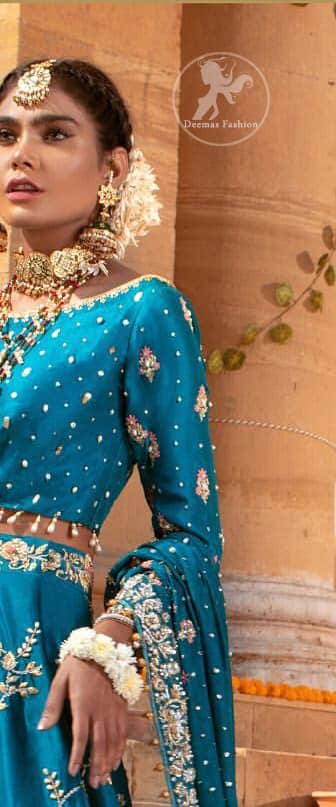 Feel glamorous in our venice blue blouse skirt with fascinating embellishment on neckline with silver kora dabka, pearl and sequins. The bridal stands out due to its uniqueness and the perfect fusion of modern cut and traditional embroidery. Blouse has simply sprinkled with perals and lehenga has embroidered applique on bottom and embellished waist belt. It is coordinated with tissue dupatta which is sprinkled with sequins all over it. It is further furnished with four sided embellished border.