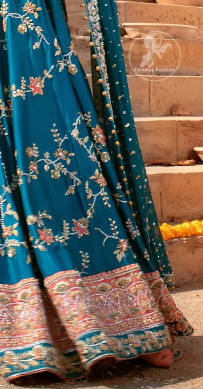 Feel glamorous in our venice blue blouse skirt with fascinating embellishment on neckline with silver kora dabka, pearl and sequins. The bridal stands out due to its uniqueness and the perfect fusion of modern cut and traditional embroidery. Blouse has simply sprinkled with perals and lehenga has embroidered applique on bottom and embellished waist belt. It is coordinated with tissue dupatta which is sprinkled with sequins all over it. It is further furnished with four sided embellished border.